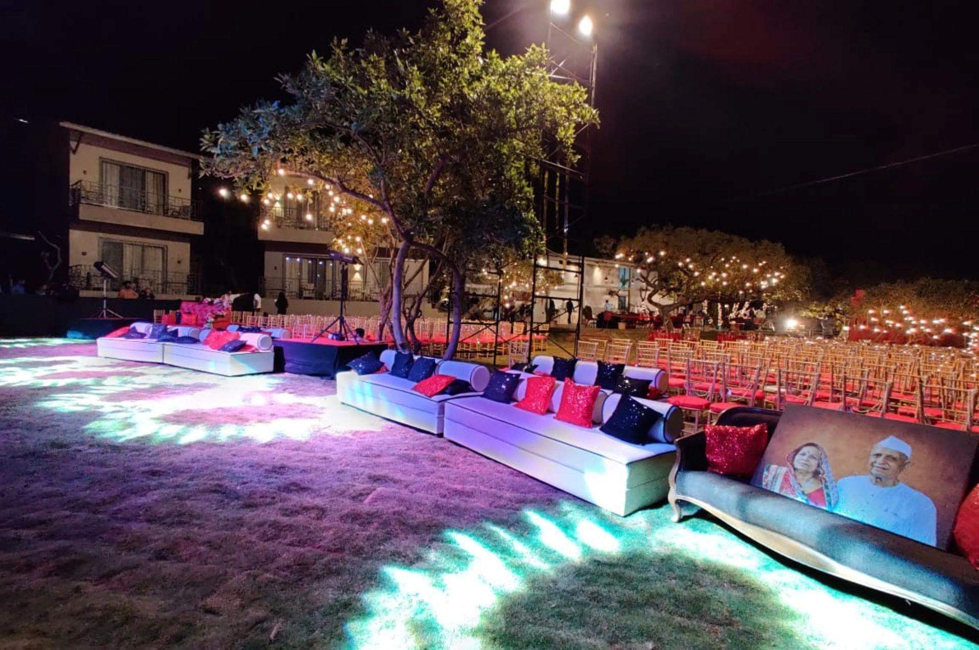 Evening wedding setup with vibrant lighting and seating at Advait Resort’s lawn.